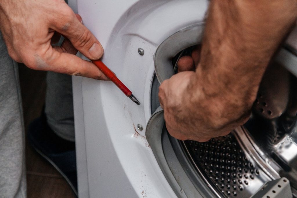 Main d'un homme faisant shunter la sécurité de porte d'un lave-linge