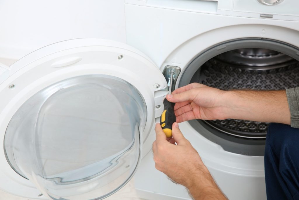 Une personne effectuant une réparation de la porte d'un lave-linge