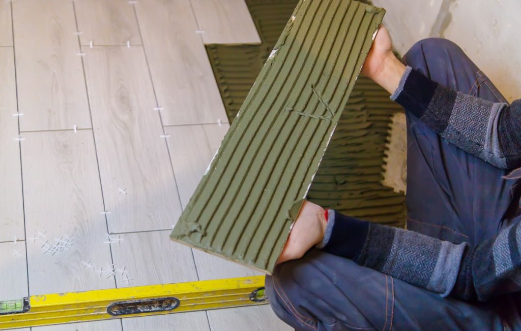 Un travailleur appliquant de la colle carrelage pour rattraper le niveau du sol