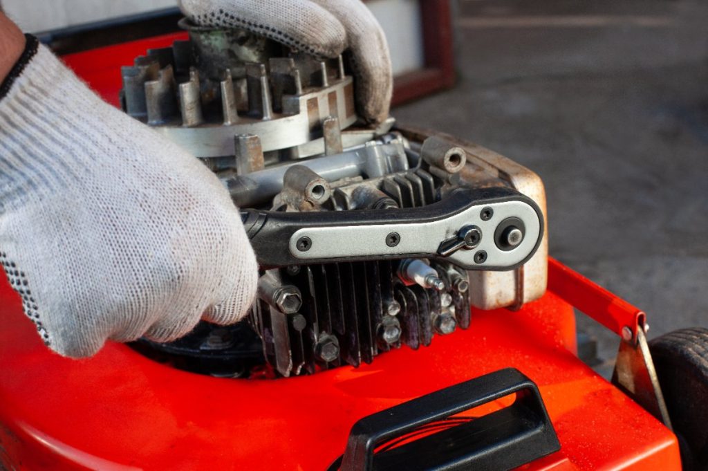 Une personne portant un gant et changeant un ressort du Briggs & Stratton