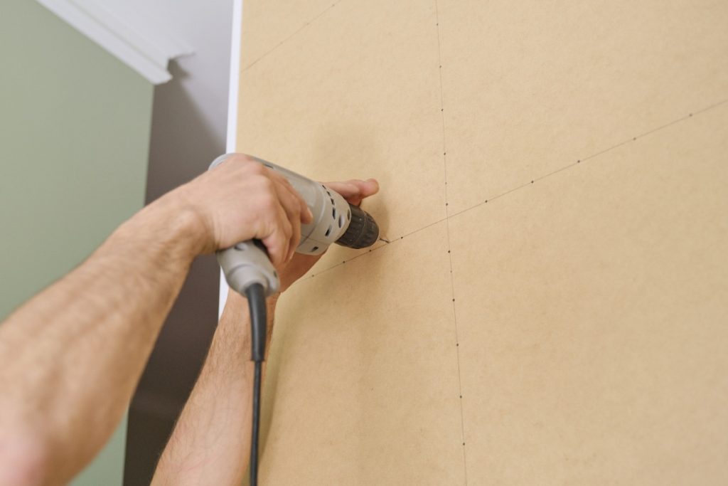 Une personne qui fait visser du placo sur le mur