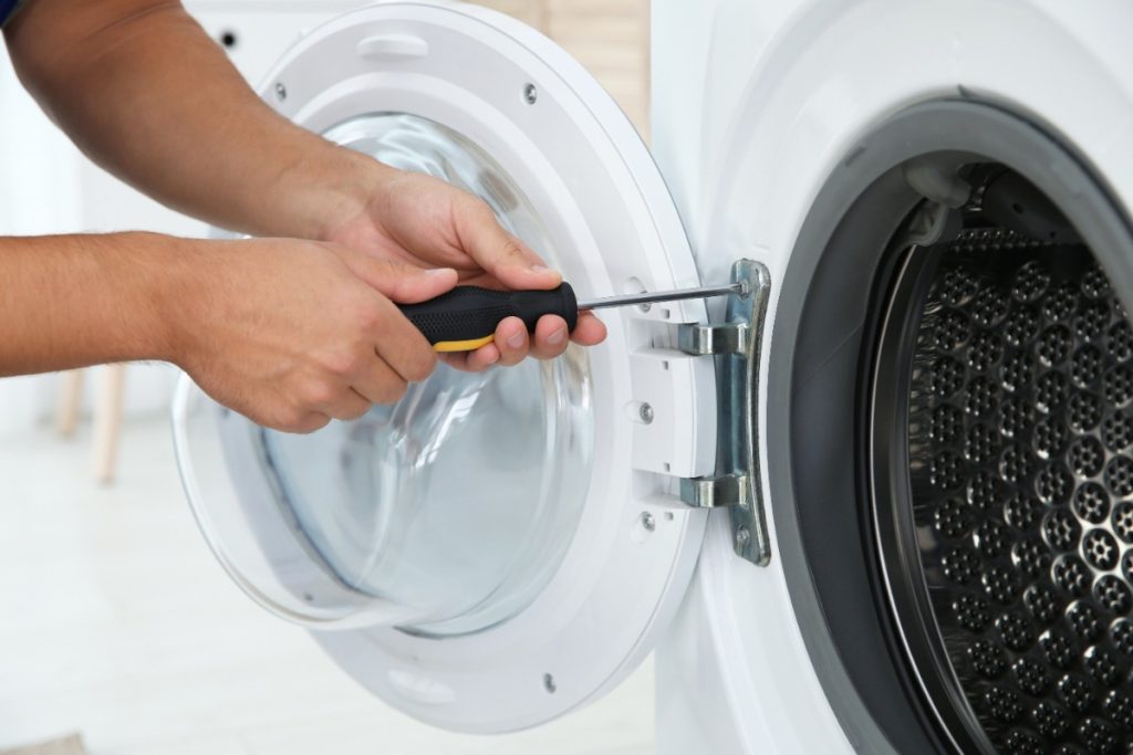 Une personne qui répare une porte de lave-linge