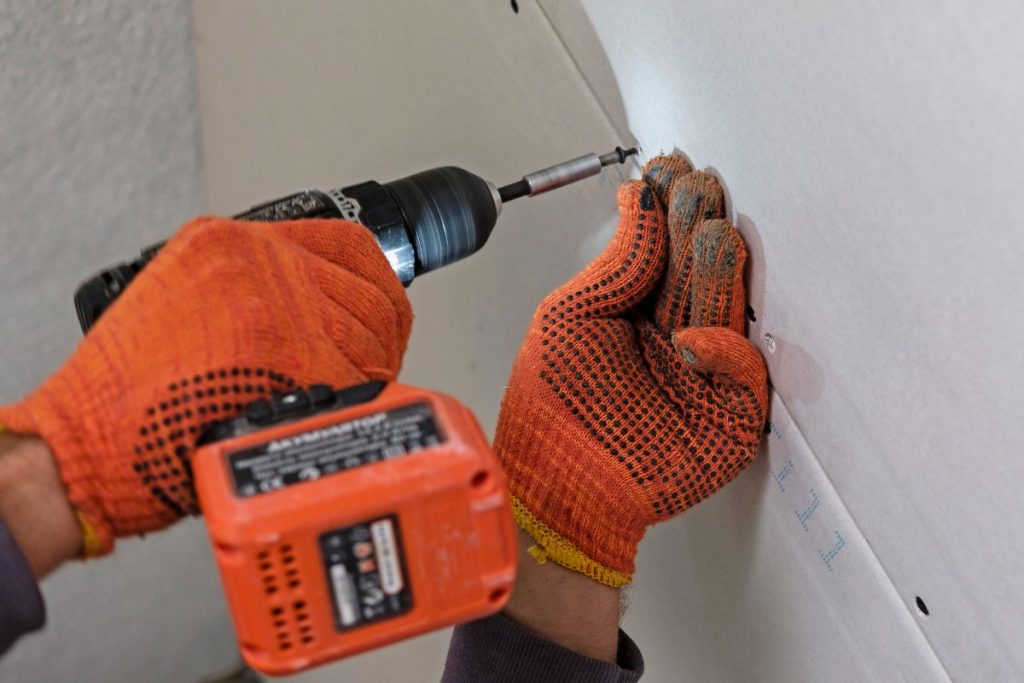 Une personne vissant du placo directement sur le mur