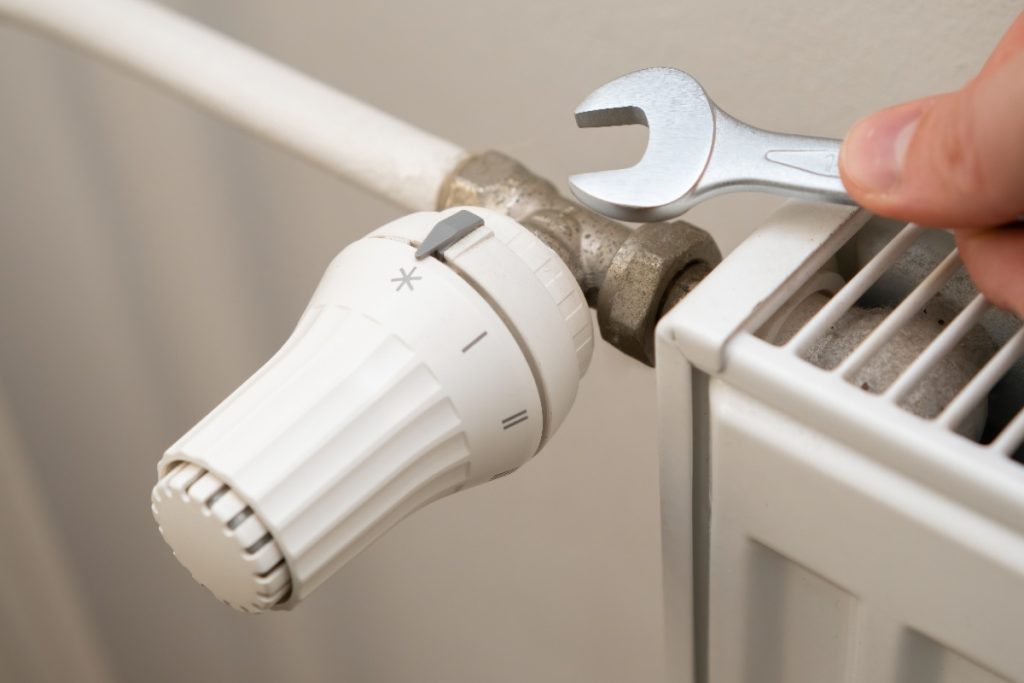 Une personne qui utilise une clé pour changer le robinet du radiateur de chauffage