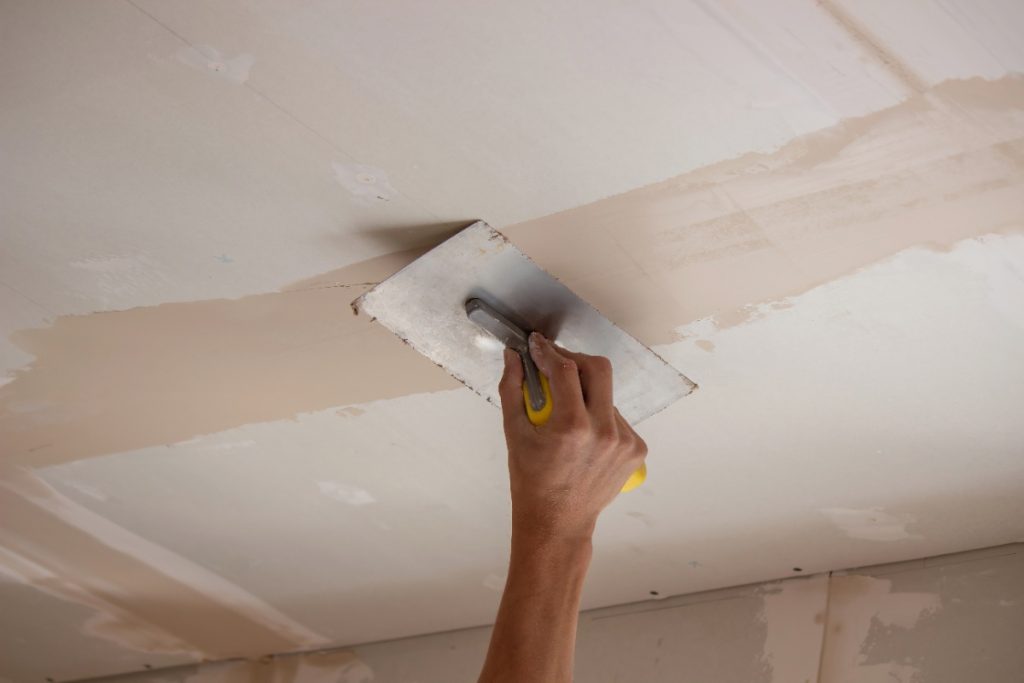 Main plâtrant le plafond