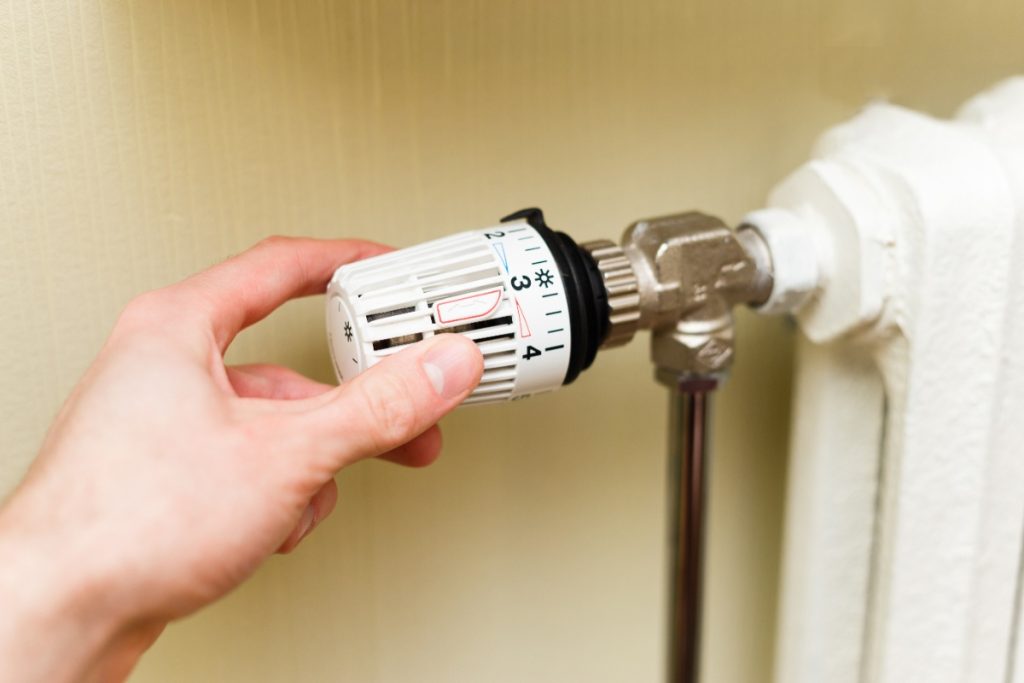 Main posée sur le robinet du radiateur de chauffage