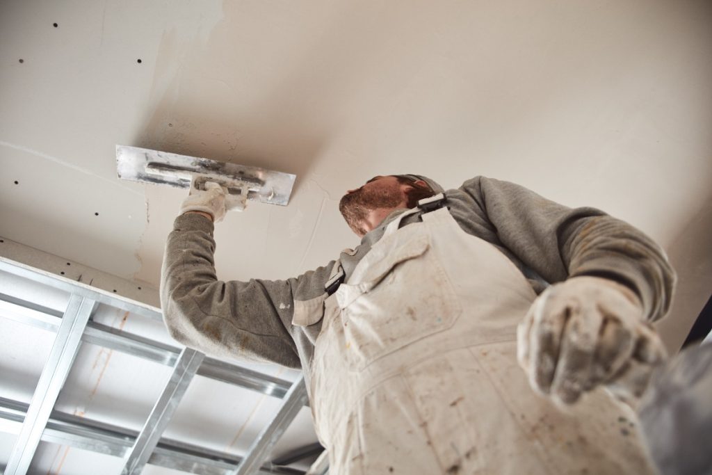 Un ouvrier qui réalise un placo sur le plafond