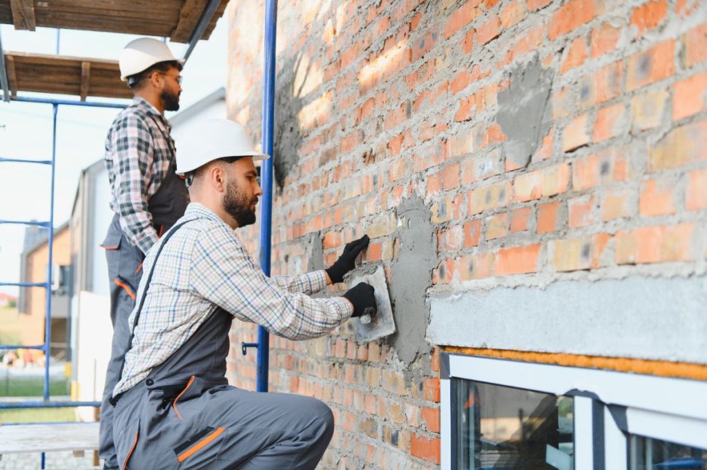 Des ouvriers qui utilisent du MAP pour enduire le mur extérieur d'une maison
