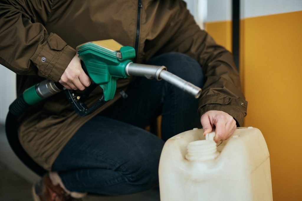 Une personne qui verse de l'essence dans le bidon