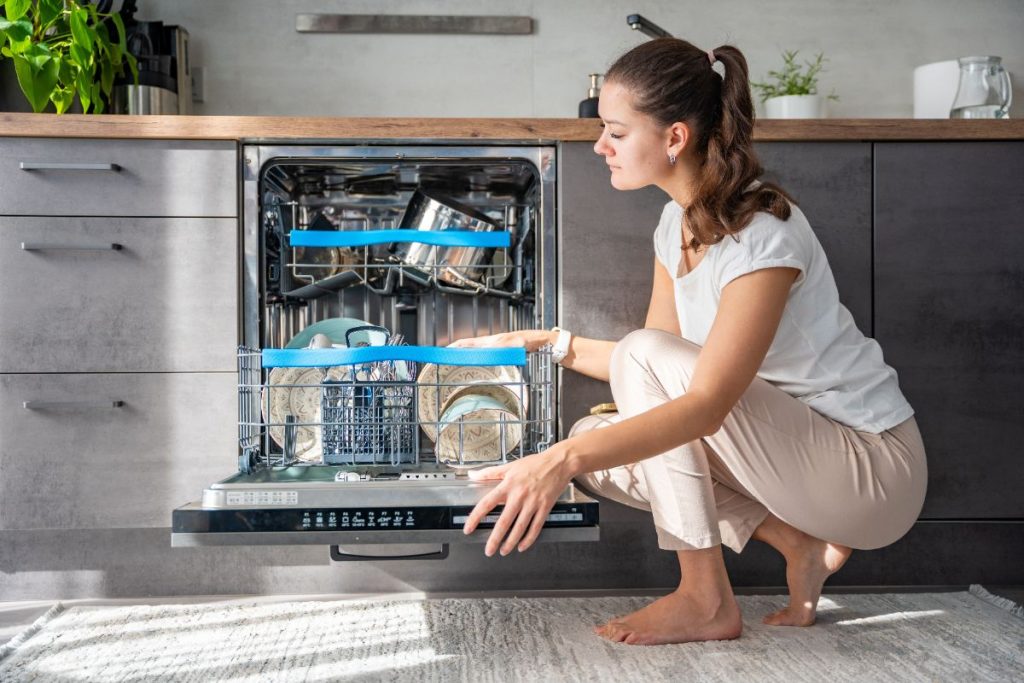 Une femme qui regarde à l'intérieur de la lave-vaisselle