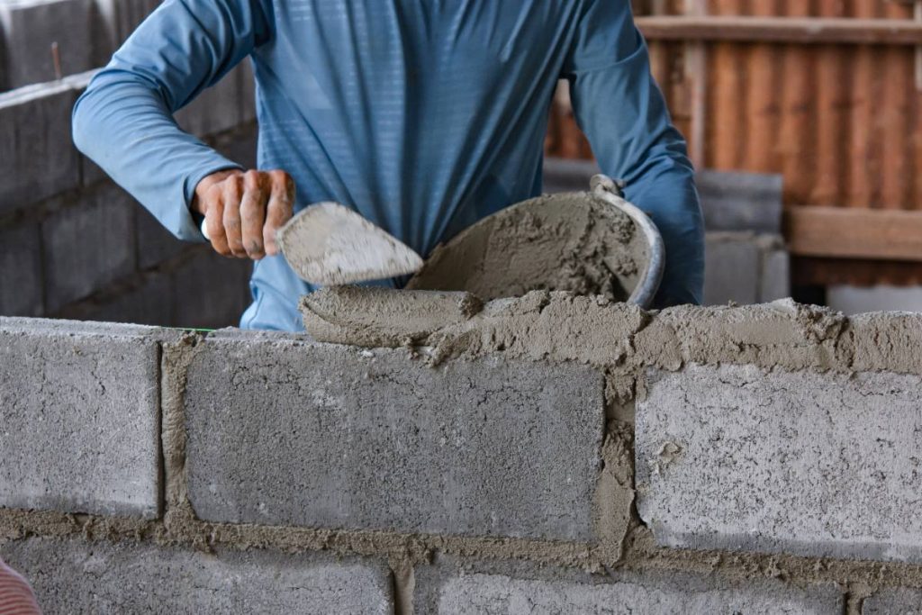 Un ouvrier appliquant du mortier sur le bloc de béton