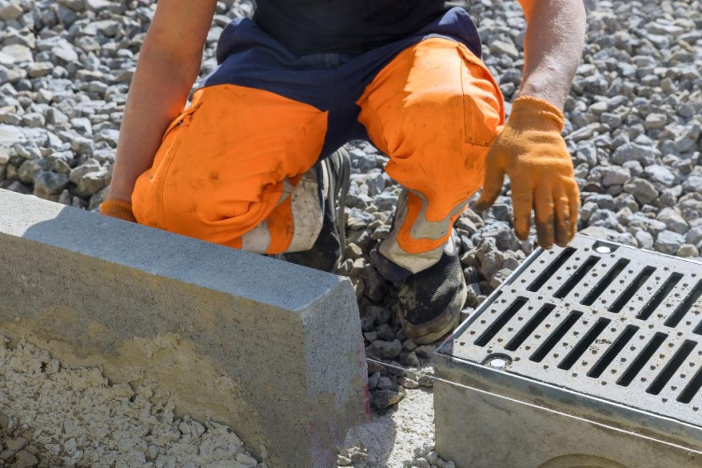Un ouvrier installant des bordures en béton pour une pose de caniveau