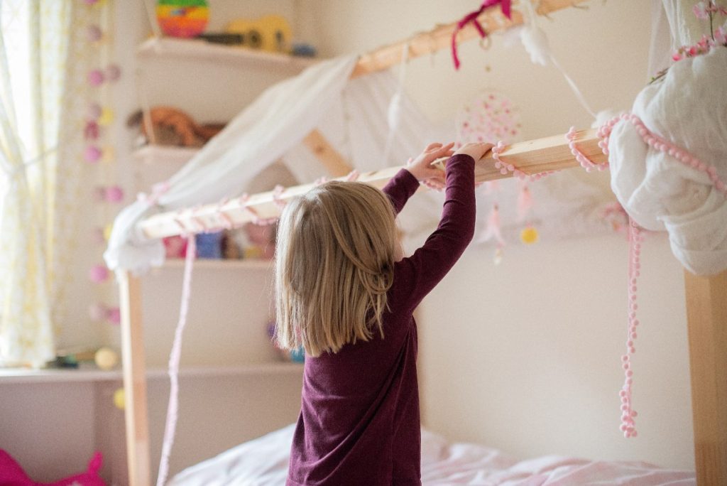 Une petite fille décorant le lit dans sa chambre