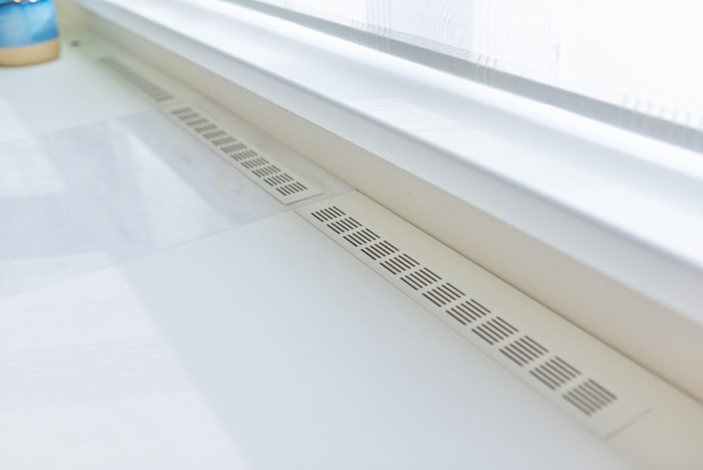 Grilles d'aération installées sous une fenêtre