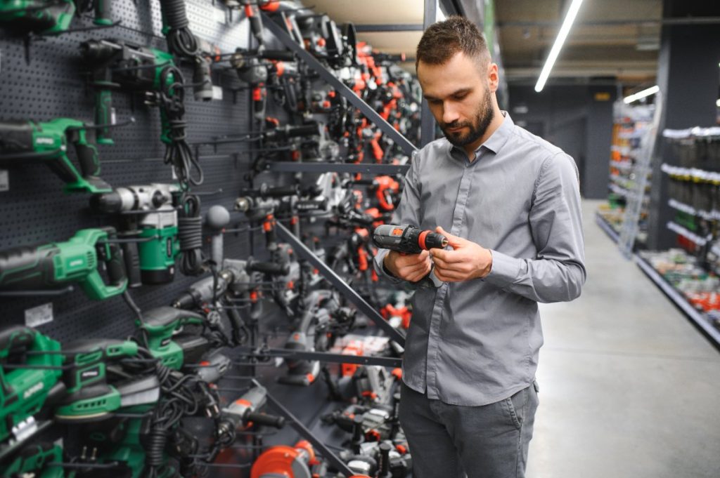Un homme choisissant une perceuse dans un magasin