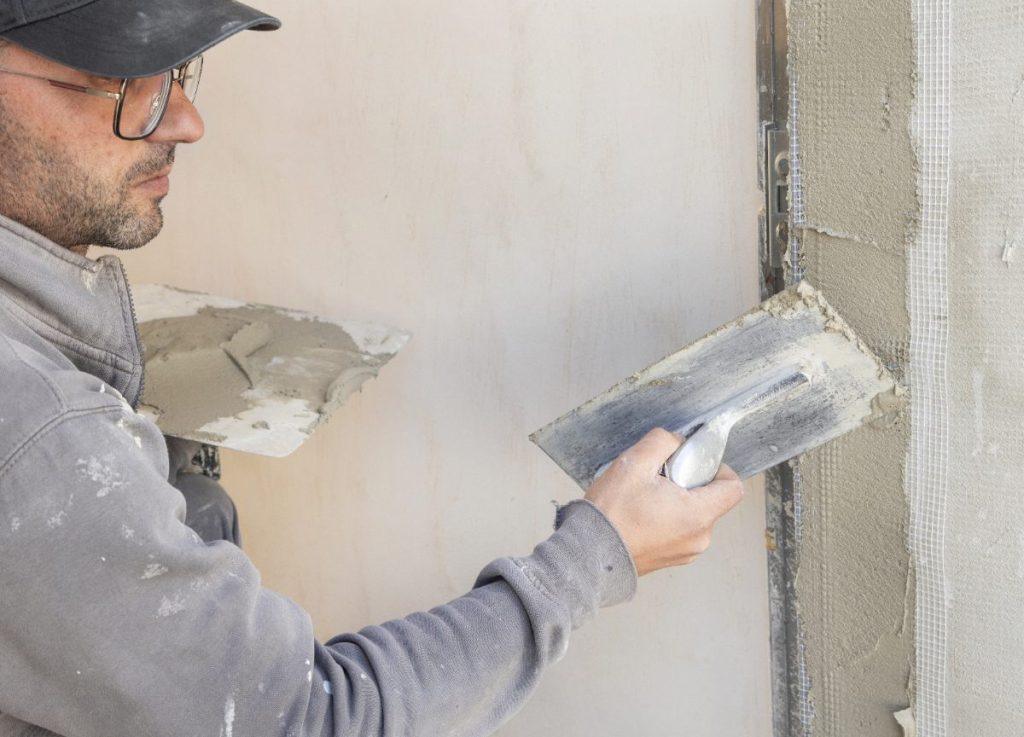 Un ouvrier de bâtiment appliquant de plâtre sur le mur