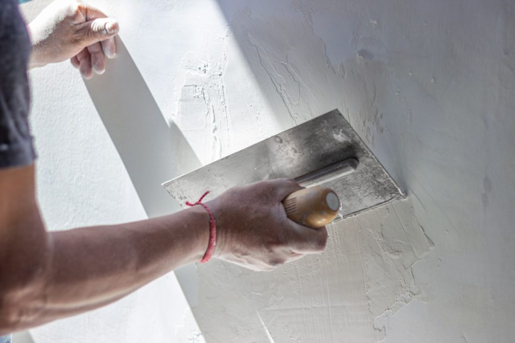 Un ouvrier faisant un plâtrage de mur avec une truelle