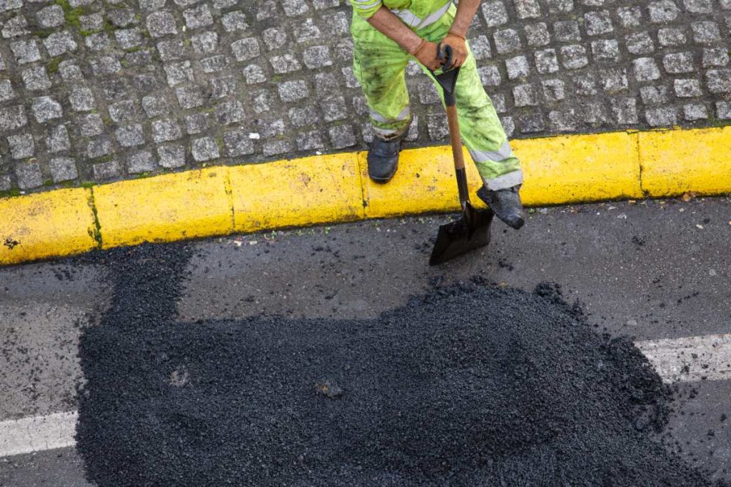 Un ouvrier tenant une pelle au bord d'une route